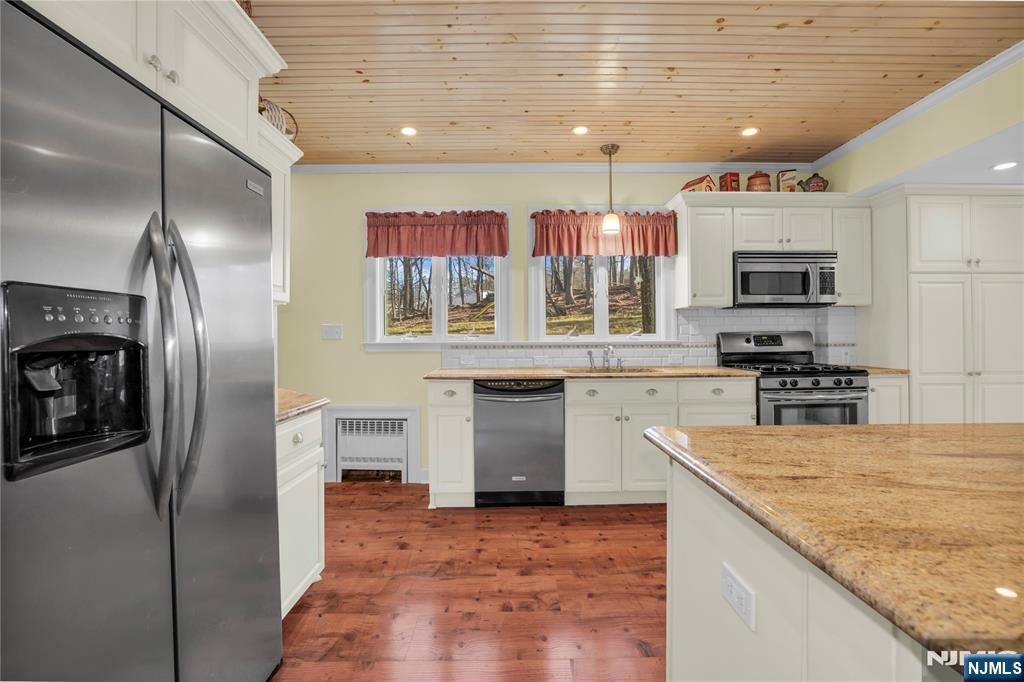 265 Little Falls Road Cedar Grove, NJ 07009 - Photo 23 of 44 a kitchen with stainless steel appliances granite countertop a refrigerator a stove and a sink with wooden floor