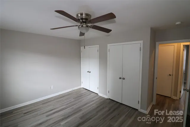 an empty room with wooden floor fan and windows
