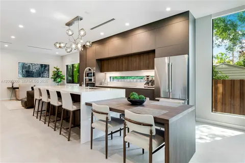 a kitchen with stainless steel appliances kitchen island granite countertop a refrigerator a stove a sink a dining table and chairs with wooden floor