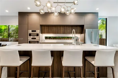 a kitchen with stainless steel appliances kitchen island a table chairs in it and wooden floors