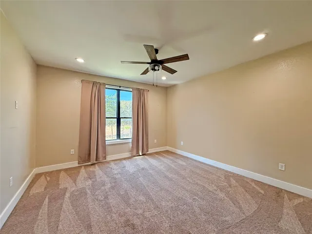 an empty room with window and ceiling fan