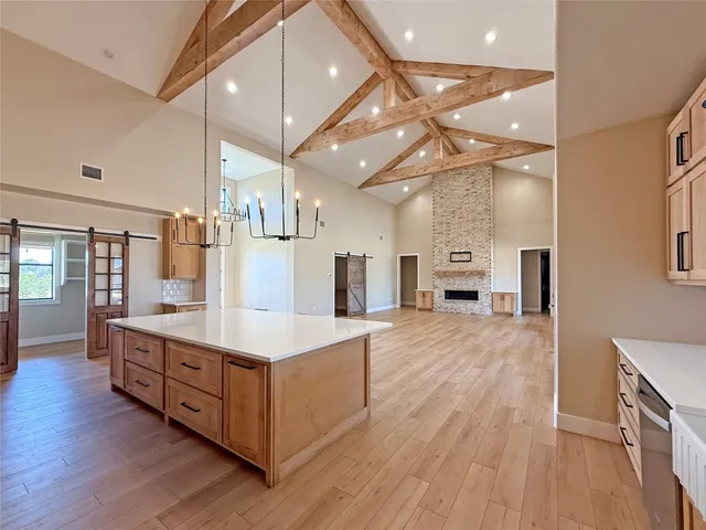 a large white kitchen with a large window a counter space and stainless steel appliances