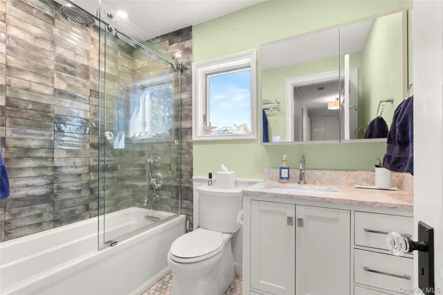 a bathroom with a sink a toilet a mirror a bathtub and shower