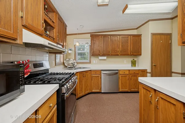 a kitchen with stainless steel appliances granite countertop a stove a sink and a microwave