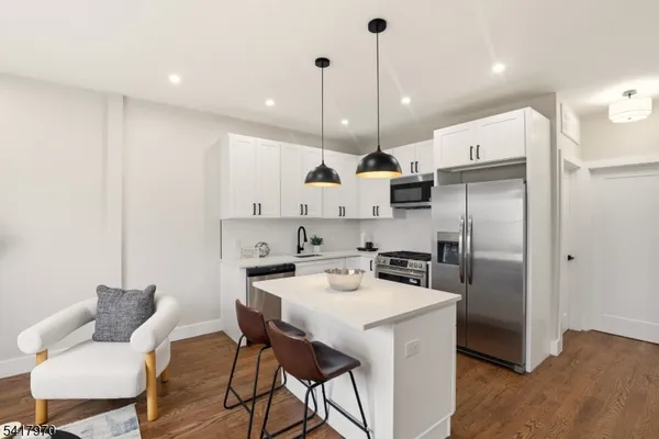 a kitchen with a refrigerator a stove a sink and a dining table with wooden floor