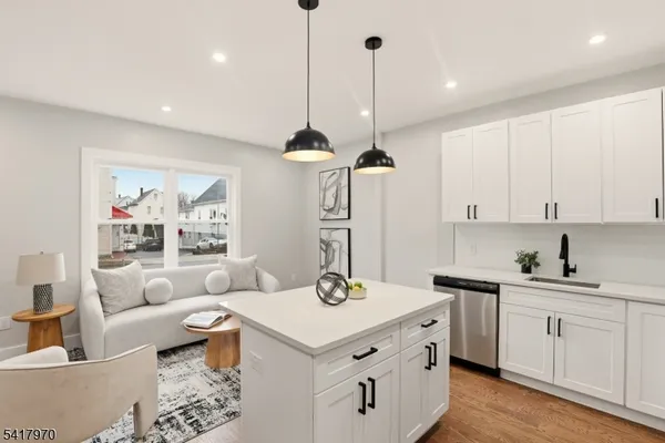 a kitchen with a sink dishwasher a stove and white cabinets with wooden floor