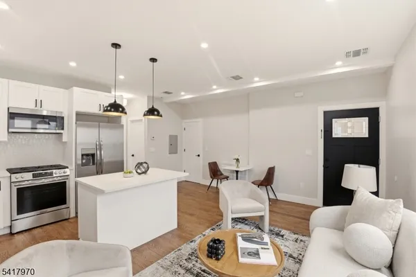 a living room with furniture a flat screen tv and kitchen view