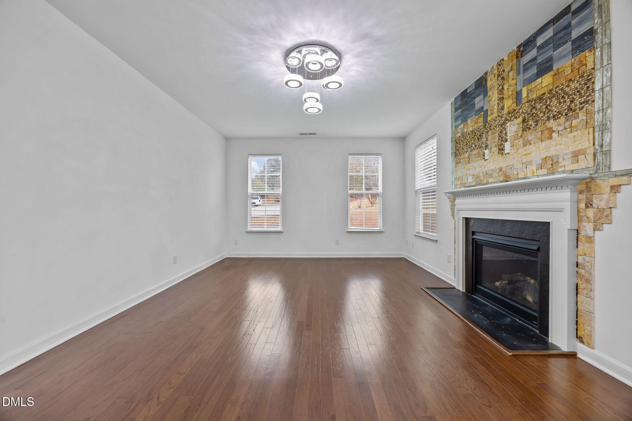 3409 South Beaver Lane Raleigh, NC 27604 - Photo 11 of 31 an empty room with wooden floor fireplace and windows