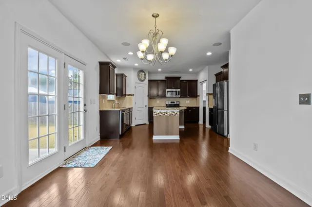 an empty room with wooden floor fireplace and windows