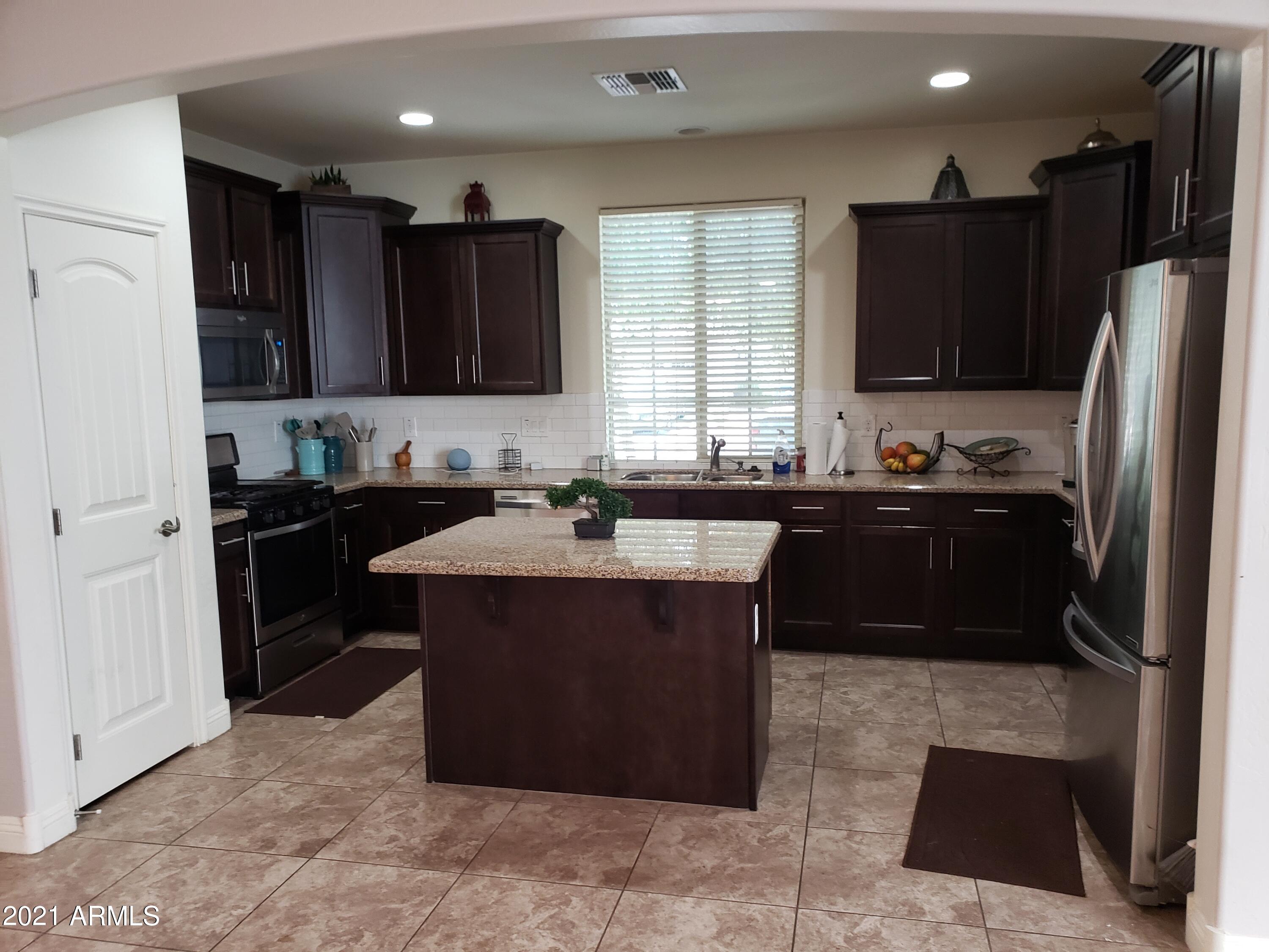 2549 North Riley Road Buckeye, AZ 85396 - Photo 7 of 46 a kitchen with a sink and a refrigerator