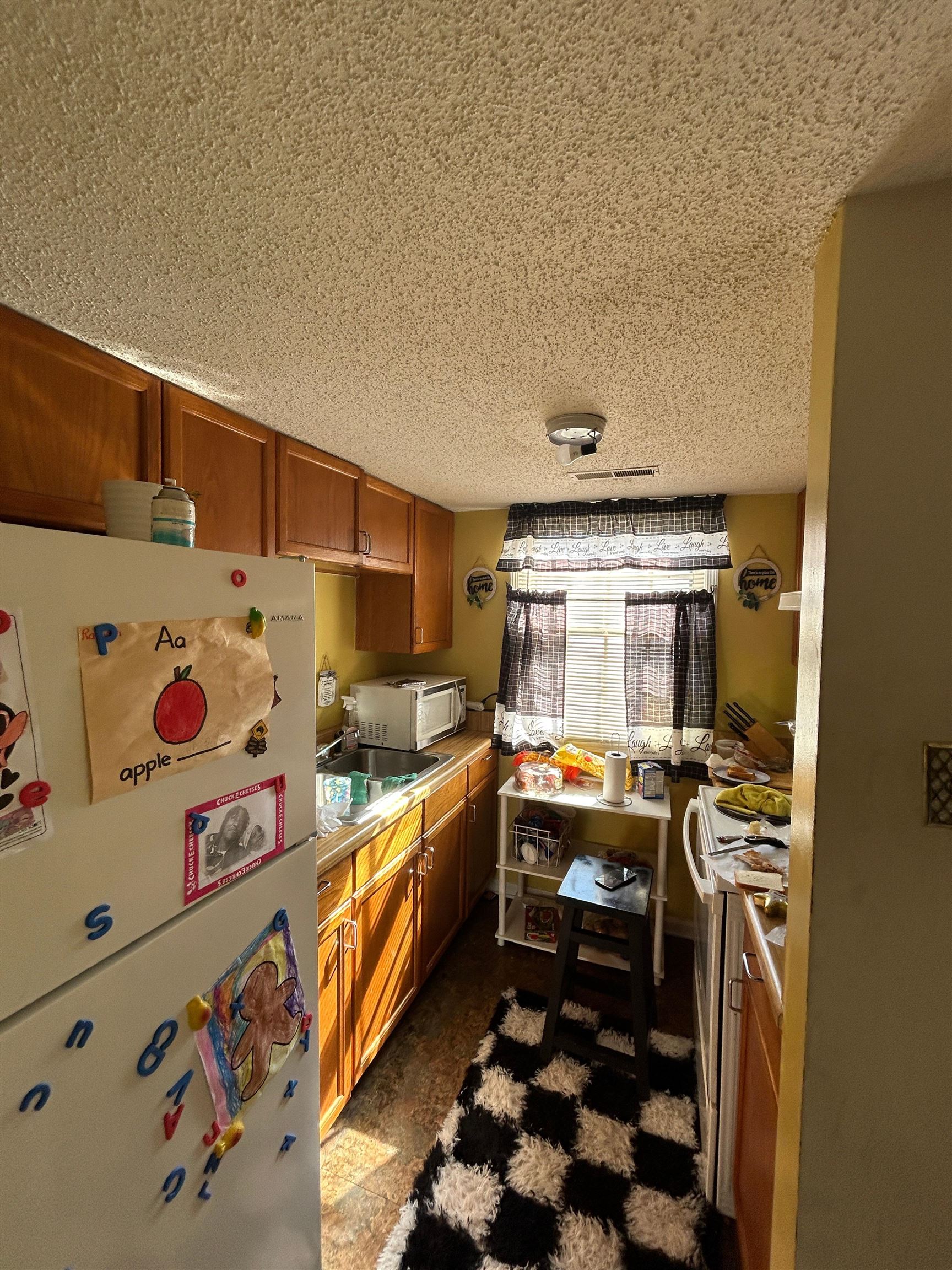3748 Station Way Memphis, TN 38115 - Photo 4 of 11 Kitchen with freestanding refrigerator, wood finish cabinetry, light countertops, stove, and a textured ceiling