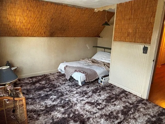 a bed sitting in a bedroom next to a small window
