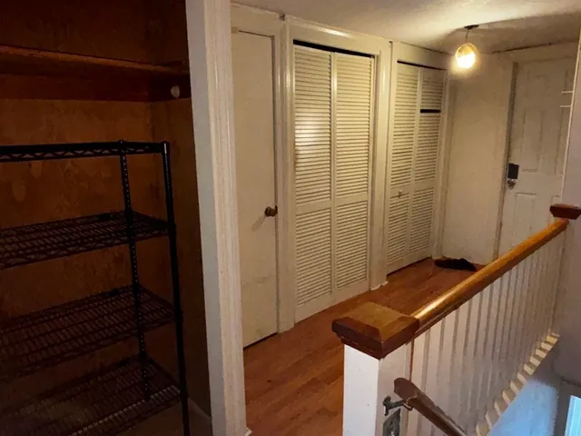 a view of a hallway with wooden floor and staircase