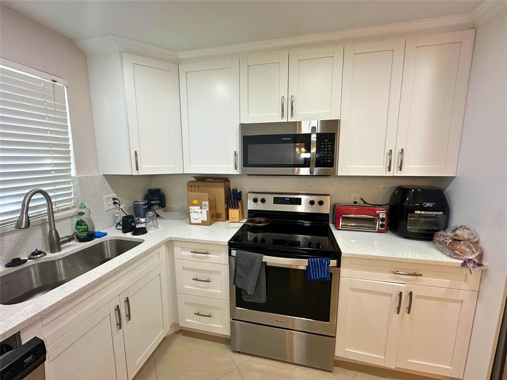 2420 DC Country Club Boulevard, Unit 306 Deerfield Beach, FL 33442 - Photo 9 of 23 a kitchen with white cabinets stainless steel appliances and sink