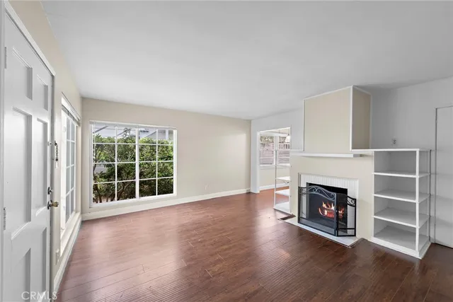 an empty room with wooden floor fireplace and windows