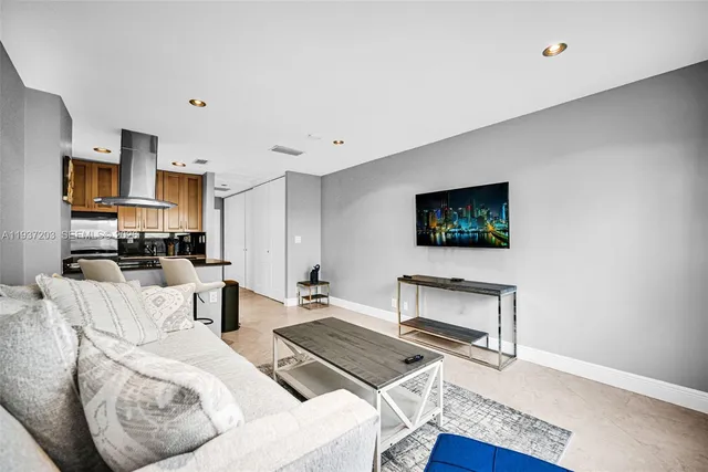 a living room with furniture a flat screen tv and kitchen view