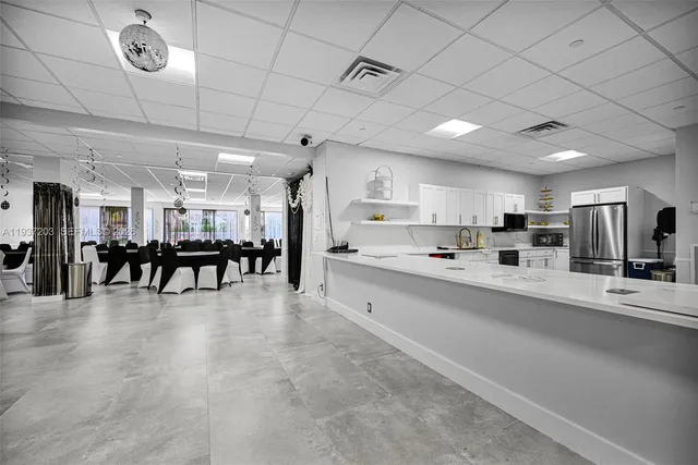 a large white kitchen with lots of counter space a sink appliances and a chandelier