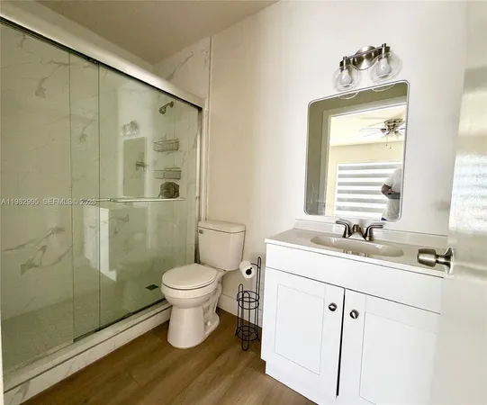 a bathroom with a granite countertop toilet a sink a shower and a mirror