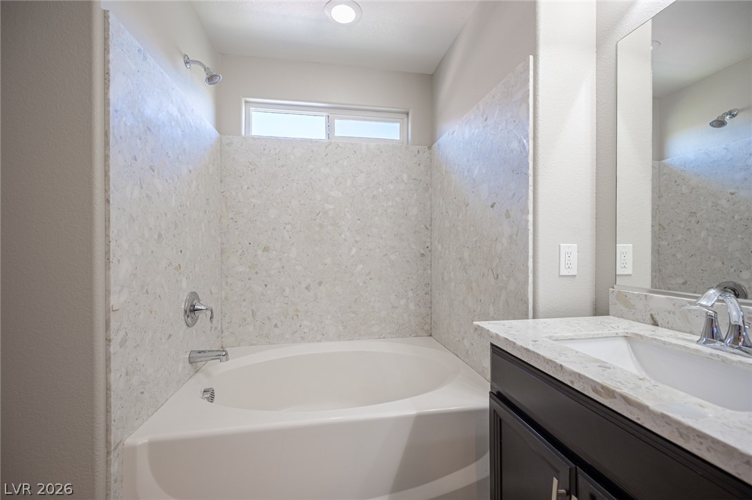 9916 Sable Point Street Las Vegas, NV 89178 - Photo 48 of 73 Indulge in a relaxing soak within this pristine corner bathtub, featuring a tiled surround and a window for natural light.