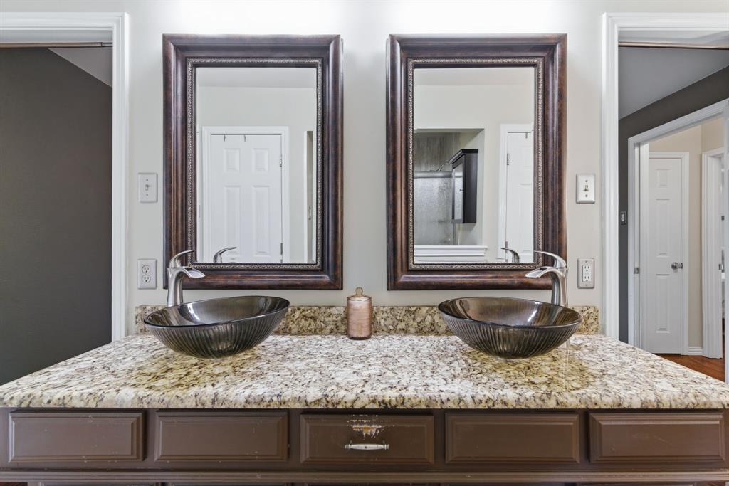 2307 Castle Rock Road Carrollton, TX 75007 - Photo 23 of 34 Bathroom vanity featuring a granite countertop, two vessel sinks, and two framed mirrors