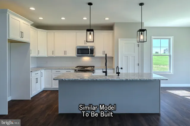 a kitchen with stainless steel appliances granite countertop a refrigerator a sink dishwasher a stove and white cabinets with wooden floor