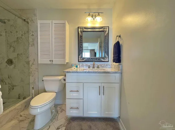 a bathroom with a granite countertop toilet sink and a mirror