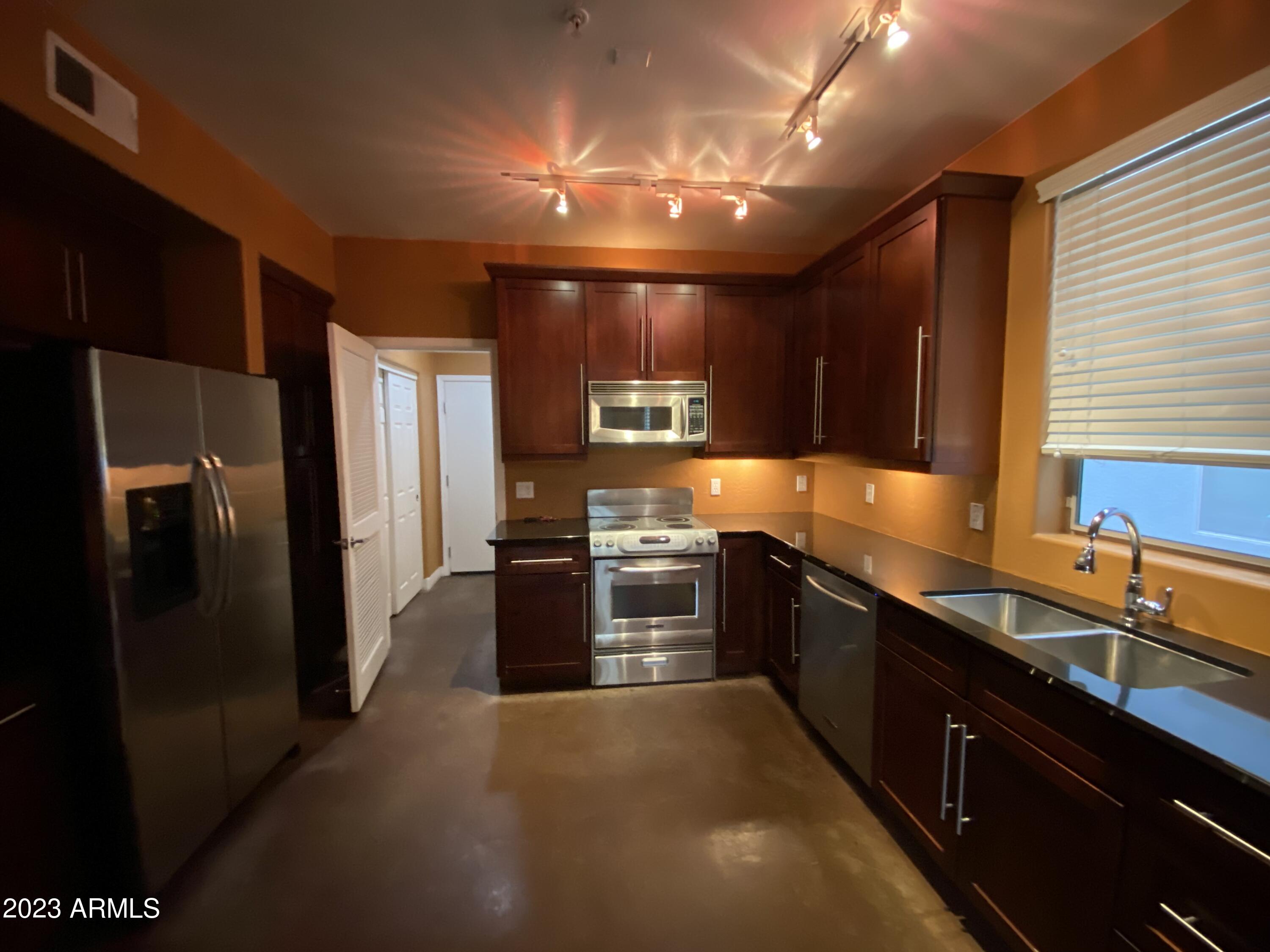 615 East Portland Street, Unit 113 Phoenix, AZ 85004 - Photo 11 of 28 a large kitchen with stainless steel appliances granite countertop a refrigerator and a sink
