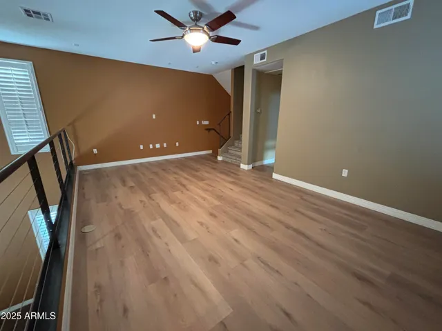 a view of an empty room with window and wooden floor