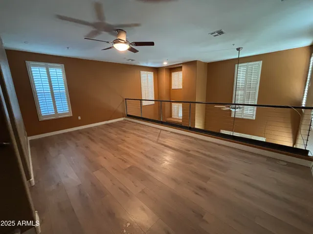 a view of an empty room with window and wooden floor