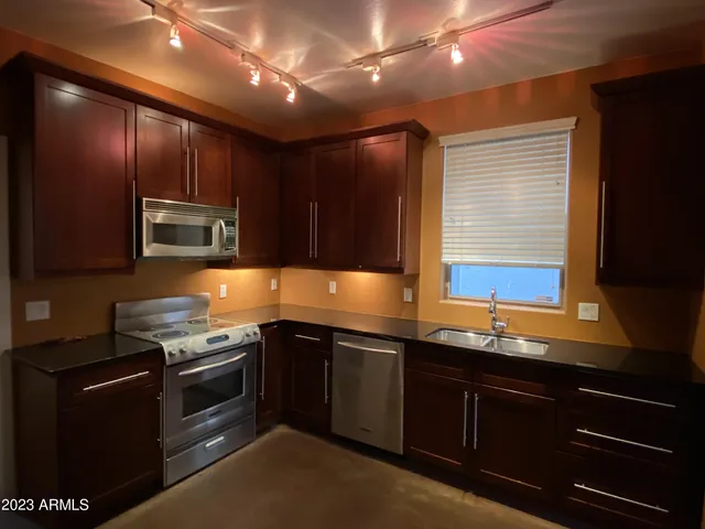 a large kitchen with stainless steel appliances granite countertop a refrigerator and a sink