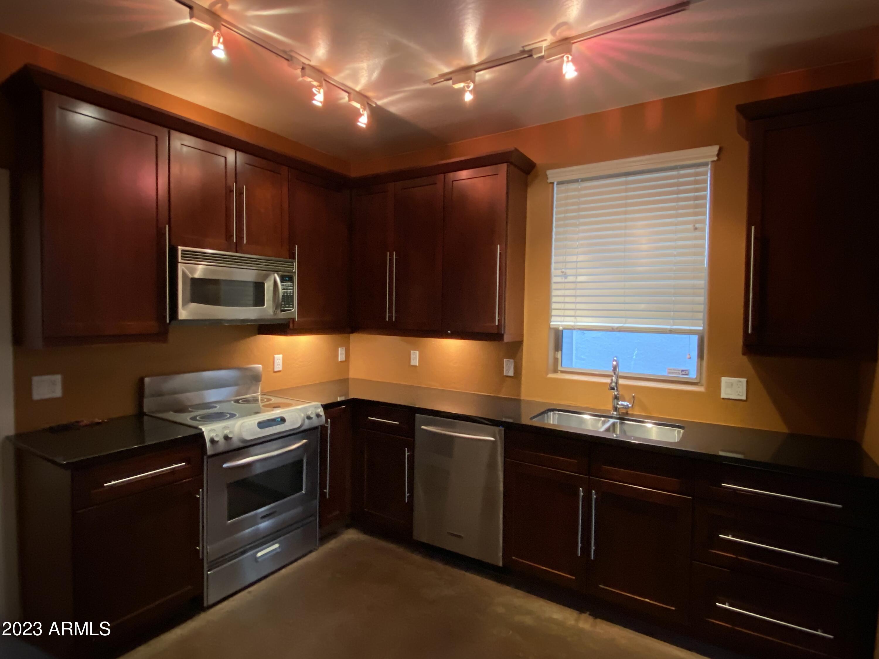 615 East Portland Street, Unit 113 Phoenix, AZ 85004 - Photo 10 of 28 a kitchen with stainless steel appliances granite countertop wooden cabinets and a stove top oven