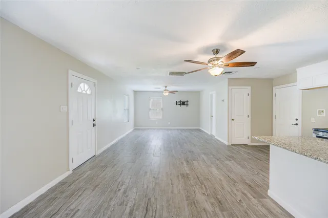 a view of an empty room with window and wooden floor