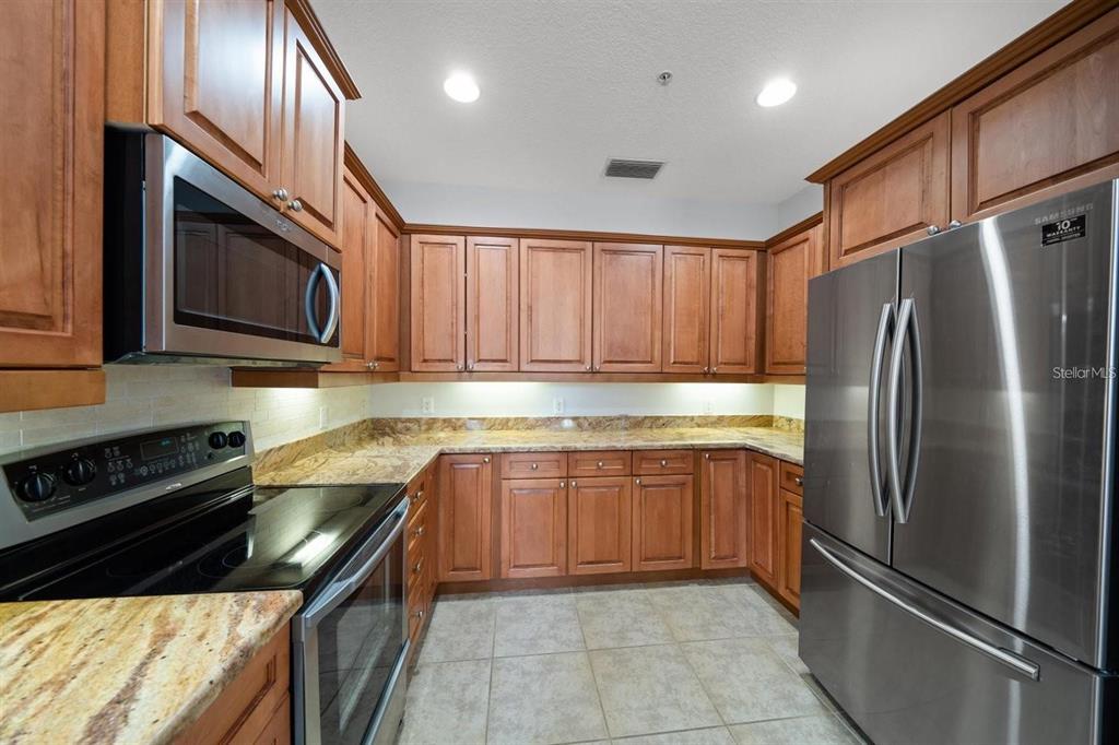 1030 Bellasol Way, Unit 201 Apollo Beach, FL 33572 - Photo 13 of 36 a kitchen with stainless steel appliances granite countertop a refrigerator sink and stove