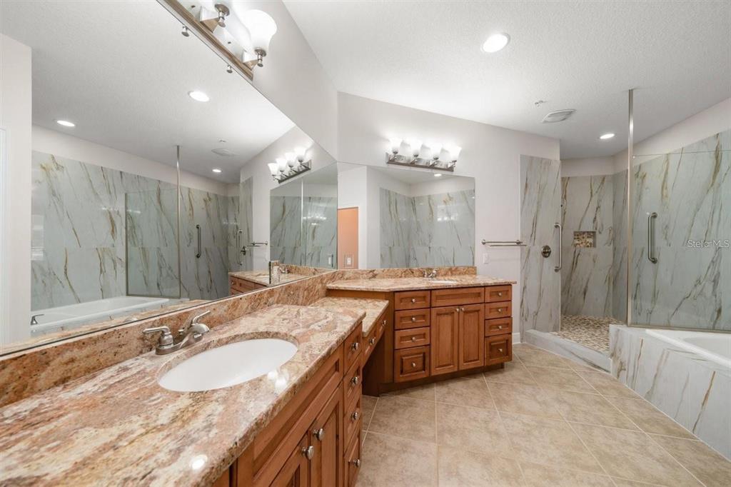 1030 Bellasol Way, Unit 201 Apollo Beach, FL 33572 - Photo 18 of 36 a bathroom with a granite countertop double vanity sink a large mirror and a bathtub
