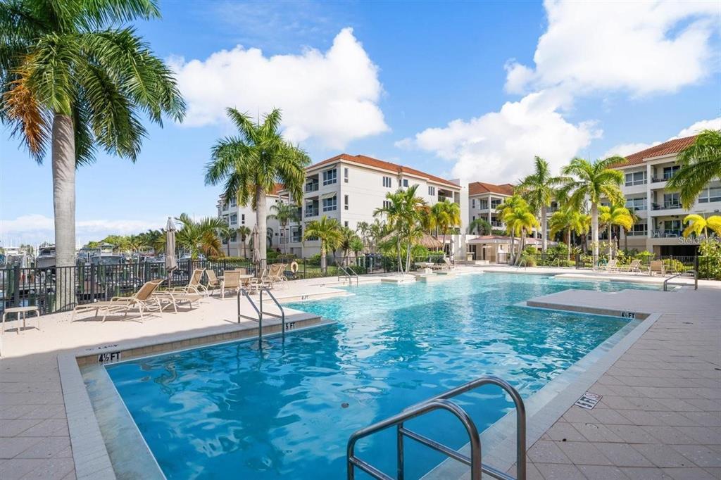 1030 Bellasol Way, Unit 201 Apollo Beach, FL 33572 - Photo 30 of 36 a view of a swimming pool with a lawn chairs under palm trees