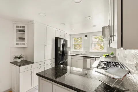 a kitchen with granite countertop a refrigerator stove and sink
