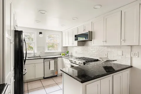 a kitchen with granite countertop a sink stove and cabinets