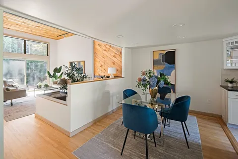 a view of a dining room with furniture a potted plant and wooden floor