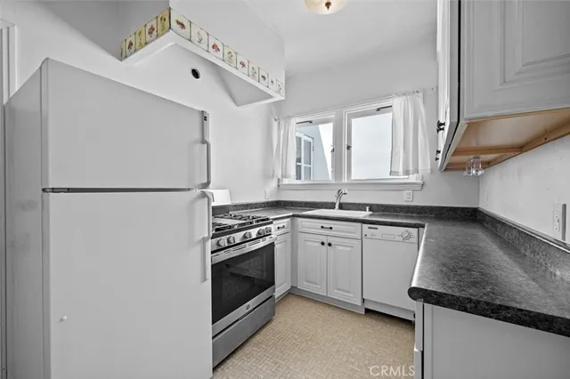 a kitchen with granite countertop a sink stove and refrigerator