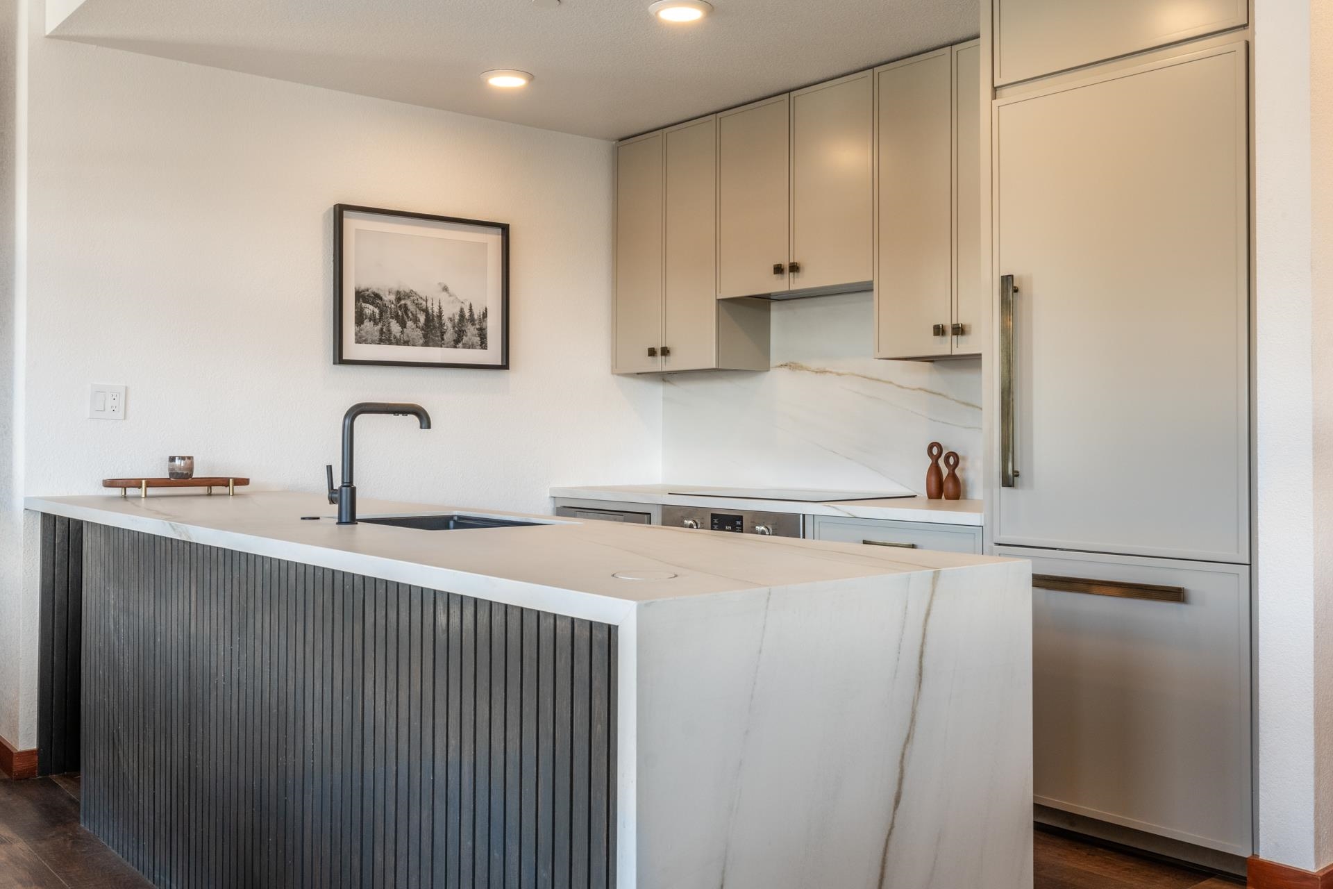 6201 Minaret Road, Unit 2430 Mammoth Lakes, CA 93546 - Photo 15 of 44 Modern kitchen featuring a large island with an integrated sink and black faucet, light-colored cabinetry, stainless steel appliances, and wood-finish flooring