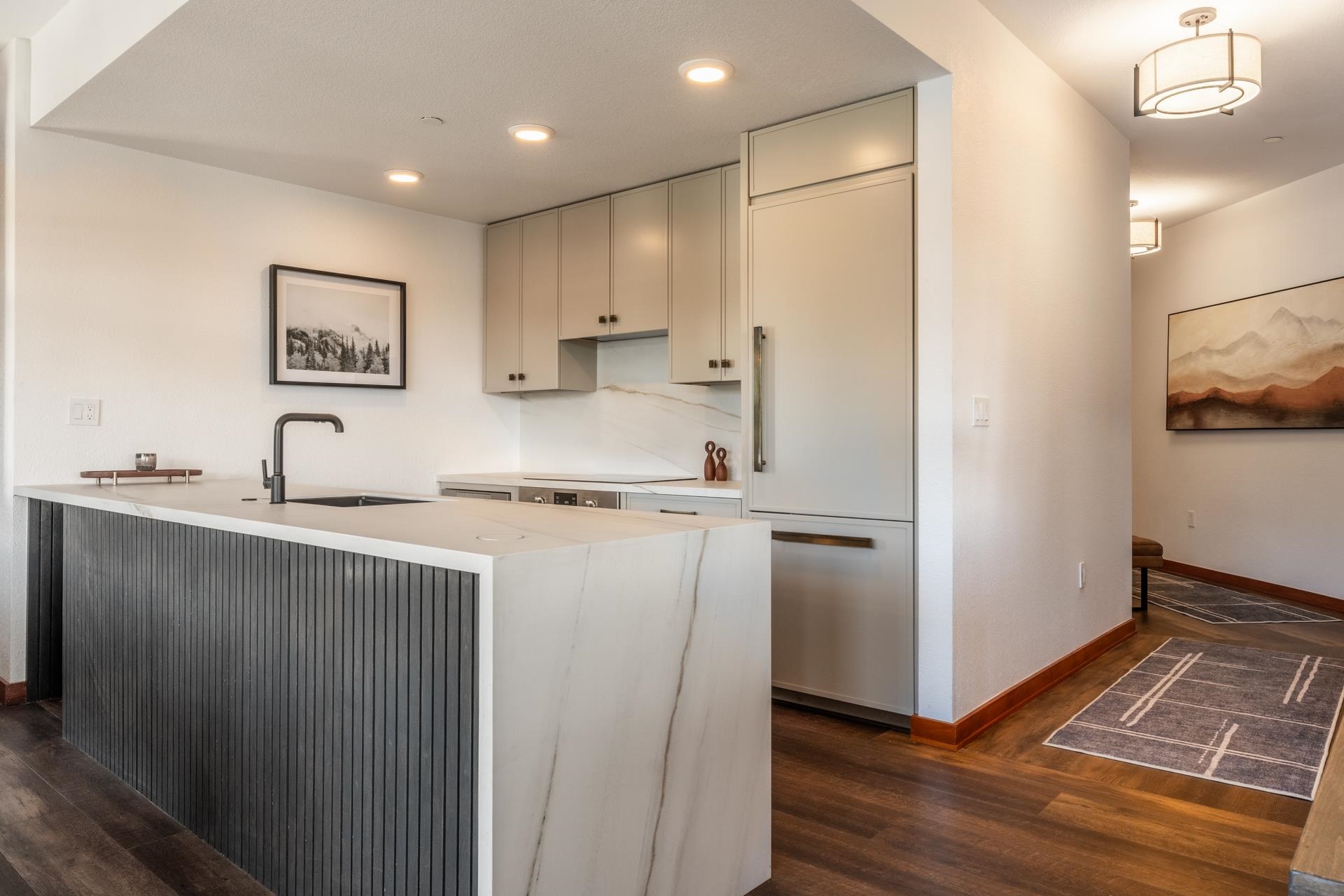 6201 Minaret Road, Unit 2430 Mammoth Lakes, CA 93546 - Photo 4 of 44 Modern kitchen featuring a waterfall island with a fluted dark wood panel, integrated sink, and matte black faucet
