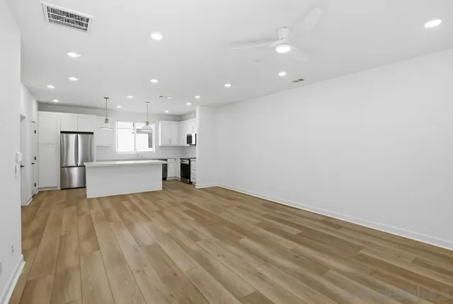 a view of empty room with wooden floor and fan