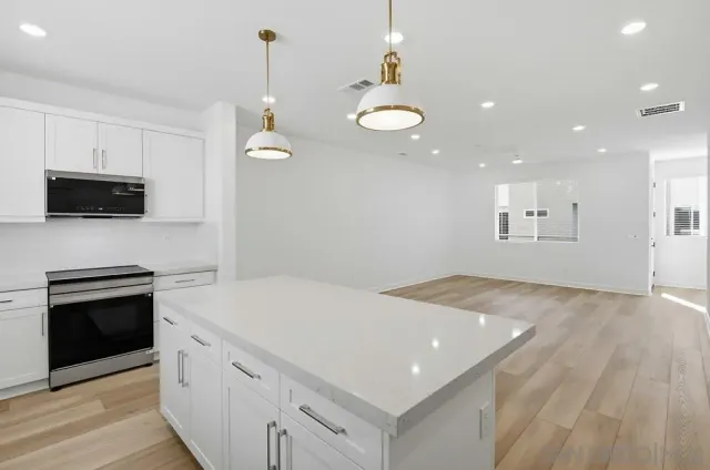 a kitchen with kitchen island white cabinets and refrigerator