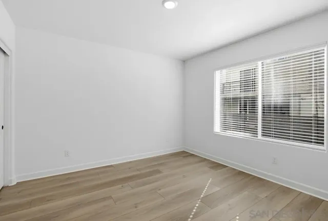 a view of an empty room with wooden floor and closet