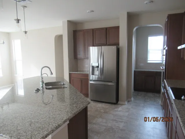 a kitchen with granite countertop a refrigerator and a sink