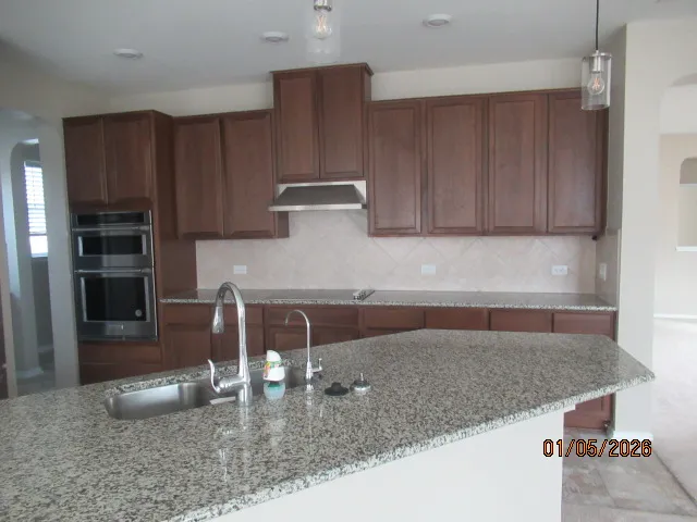 a kitchen with granite countertop a sink a stove and a wooden cabinets