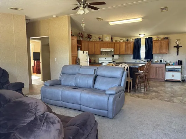 a living room with furniture and a view of kitchen