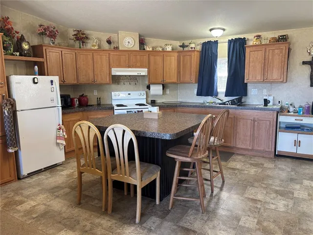 a kitchen with granite countertop a sink a stove a dining table and chairs