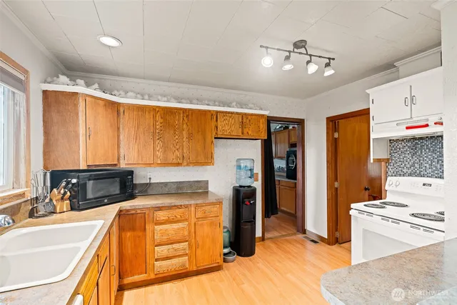 a kitchen with stainless steel appliances granite countertop a refrigerator a oven and white cabinets with wooden floors