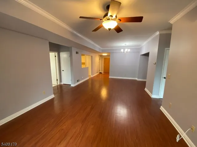 a view of an empty room with wooden floor and a ceiling fan
